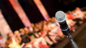 Image of a microphone in front of an audience representing Overcoming The Fear Of Speaking In Public